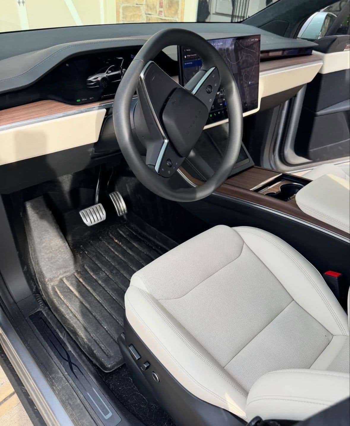 Tesla Model X driver footwell with a dirty floor mat before detailing.